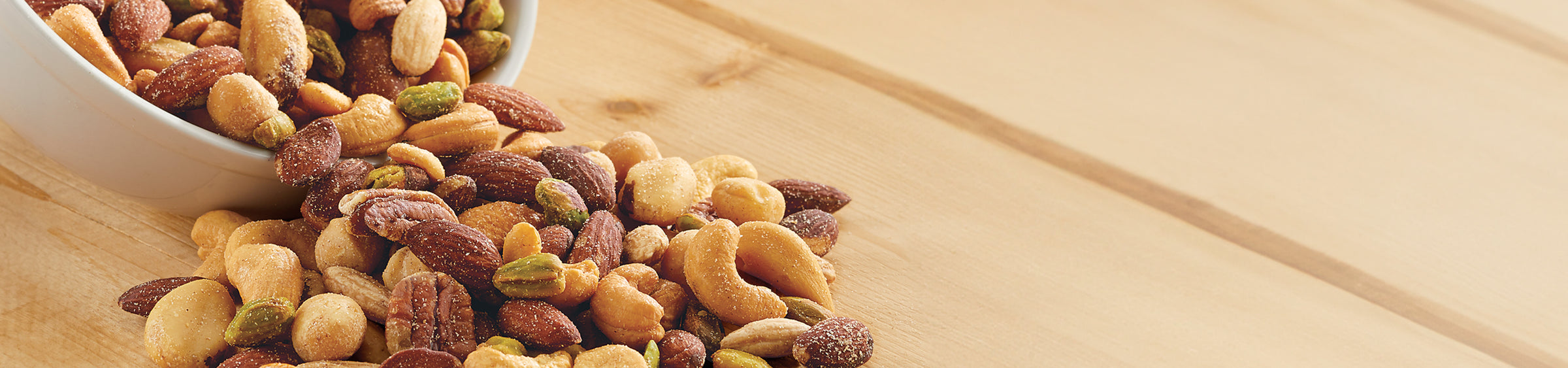 Whitley's Deluxe Nut Mix is in a white bowl on a wooden surface.